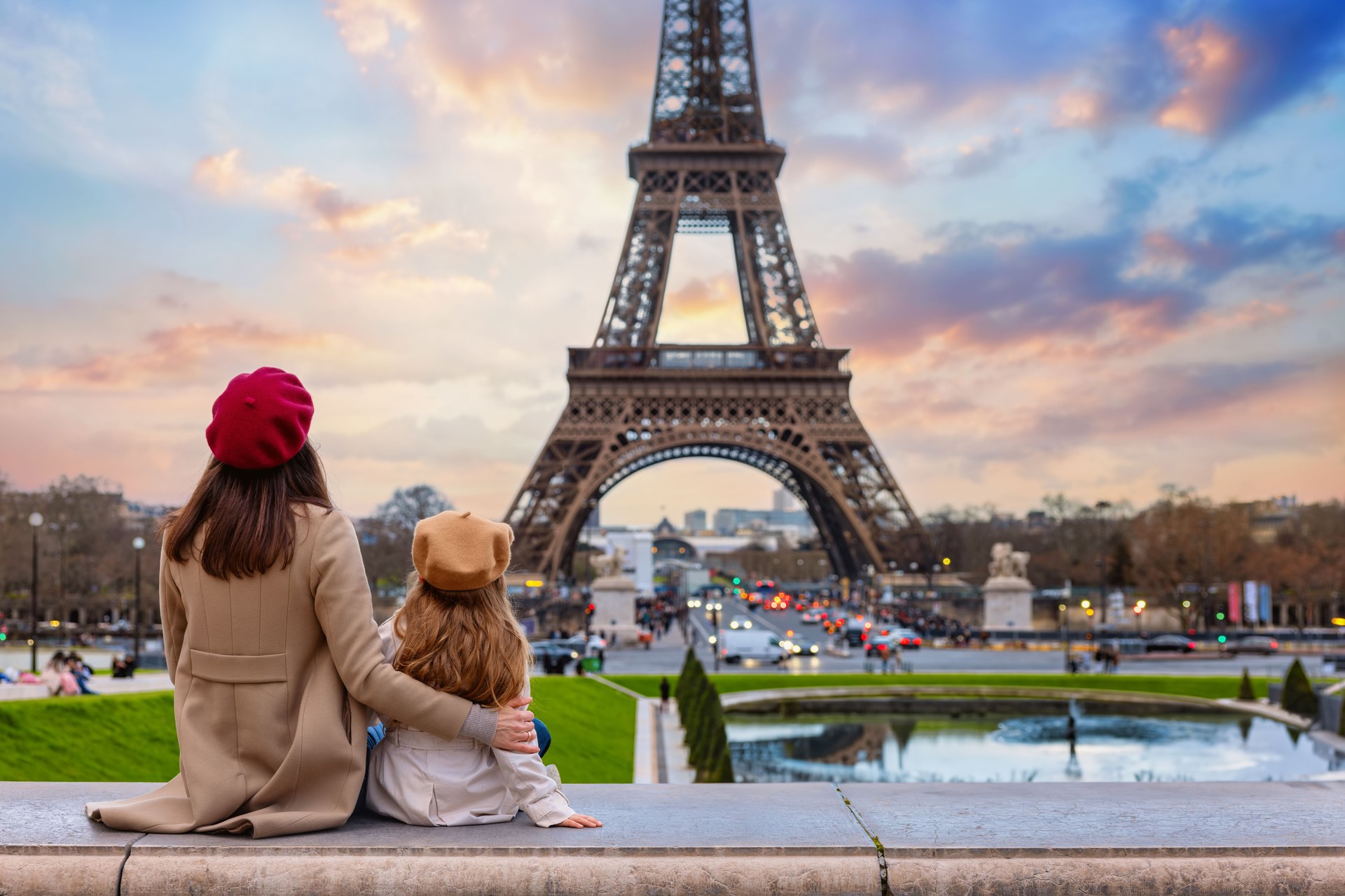 A mother and her daughter looking at the sunset view of the Eiffel Tower